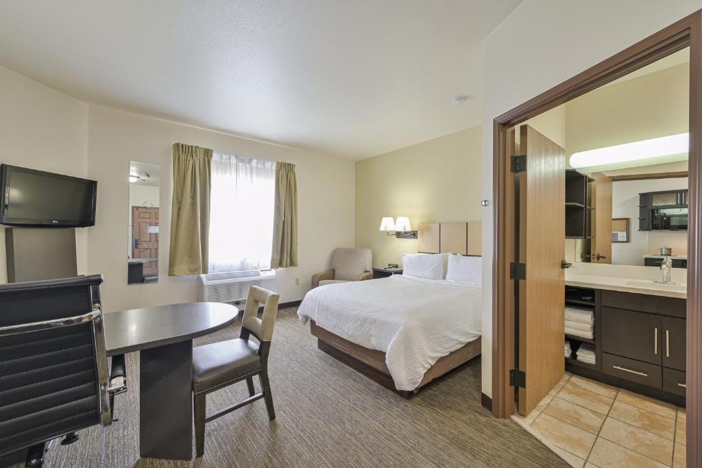 タルサにあるAffordable Suites of America Tulsaのベッドと机と洗面台があるホテルの部屋