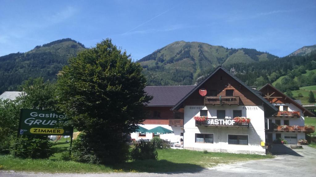a building with a sign and mountains in the background at Gasthof Gruber in Wald am Schoberpaß