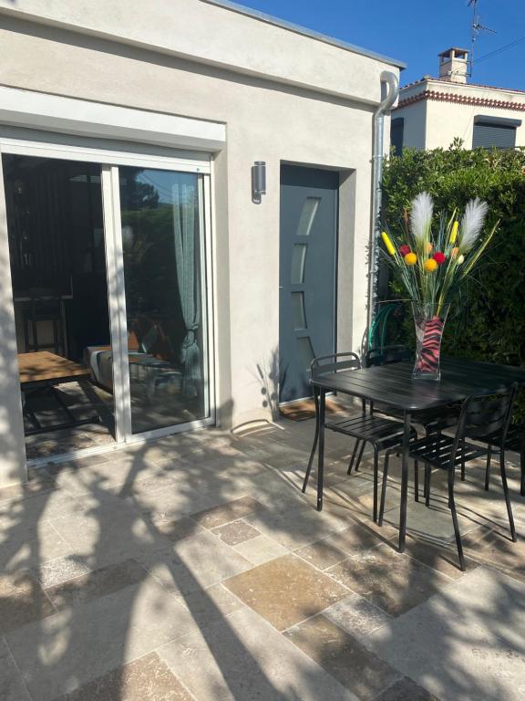 Una mesa con un jarrón de flores en un patio. en La Valenzo, en Aubagne