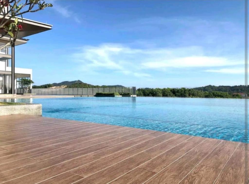 Una piscina con terraza de madera y agua. en Family Homestay, en Nilai