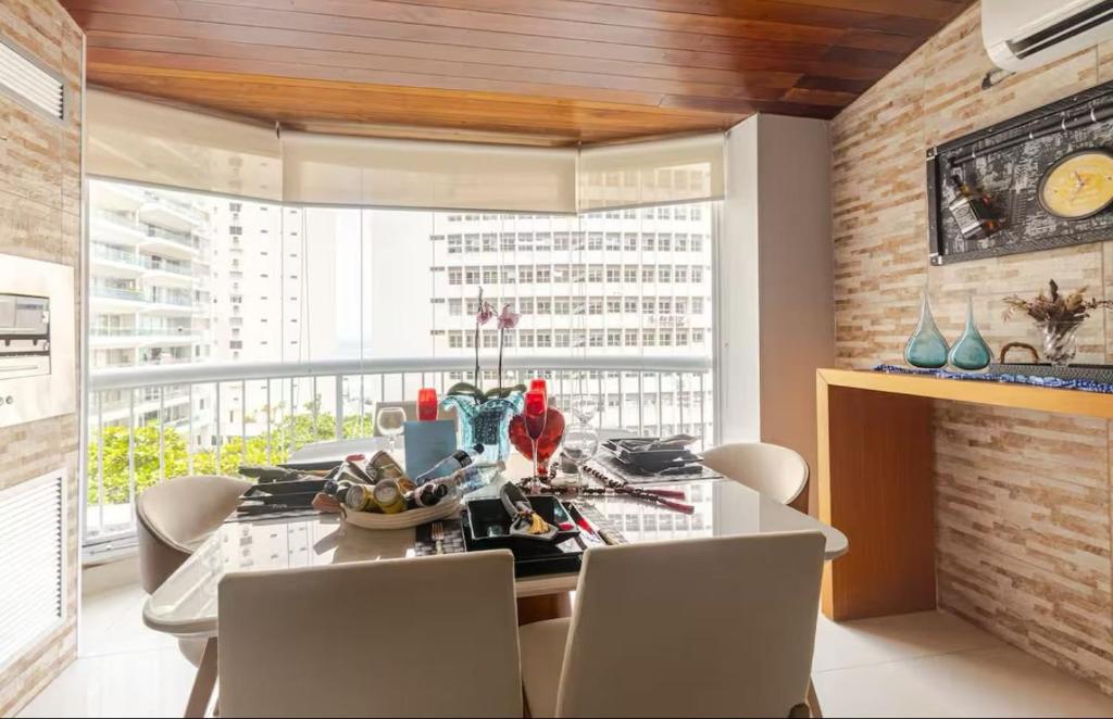 a dining room with a table and chairs and a window at Flat ao lado do Mar Four Season in Guarujá