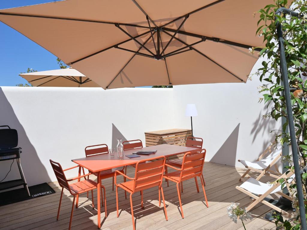 une table en bois avec des chaises et un parasol dans l'établissement Maison de plain-pied avec Parking et Climatisation près de Châtelaillon-Plage - FR-1-706-33, à Saint-Vivien