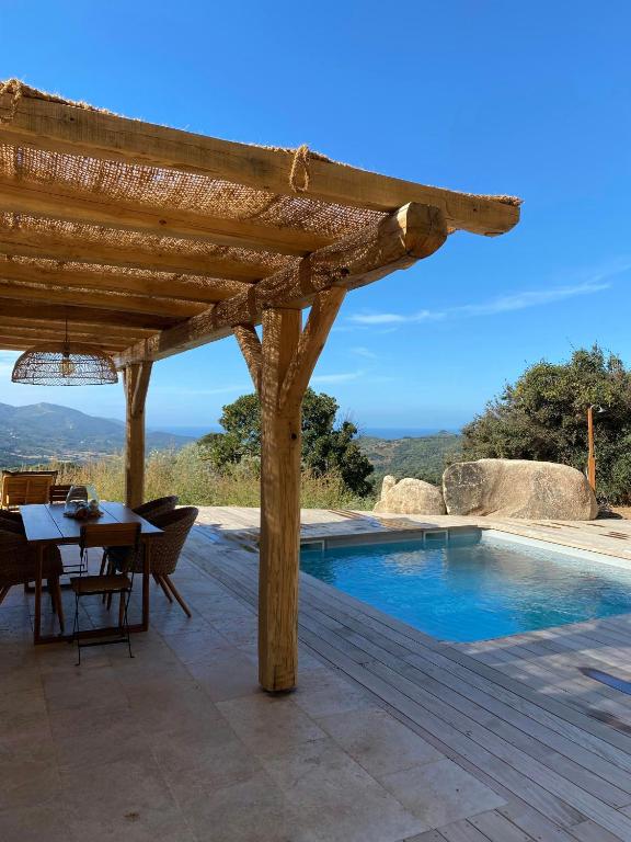 une terrasse en bois avec une table et une piscine dans l'établissement Beautiful Stone House With Sea View In Corsica, à Sari-dʼOrcino