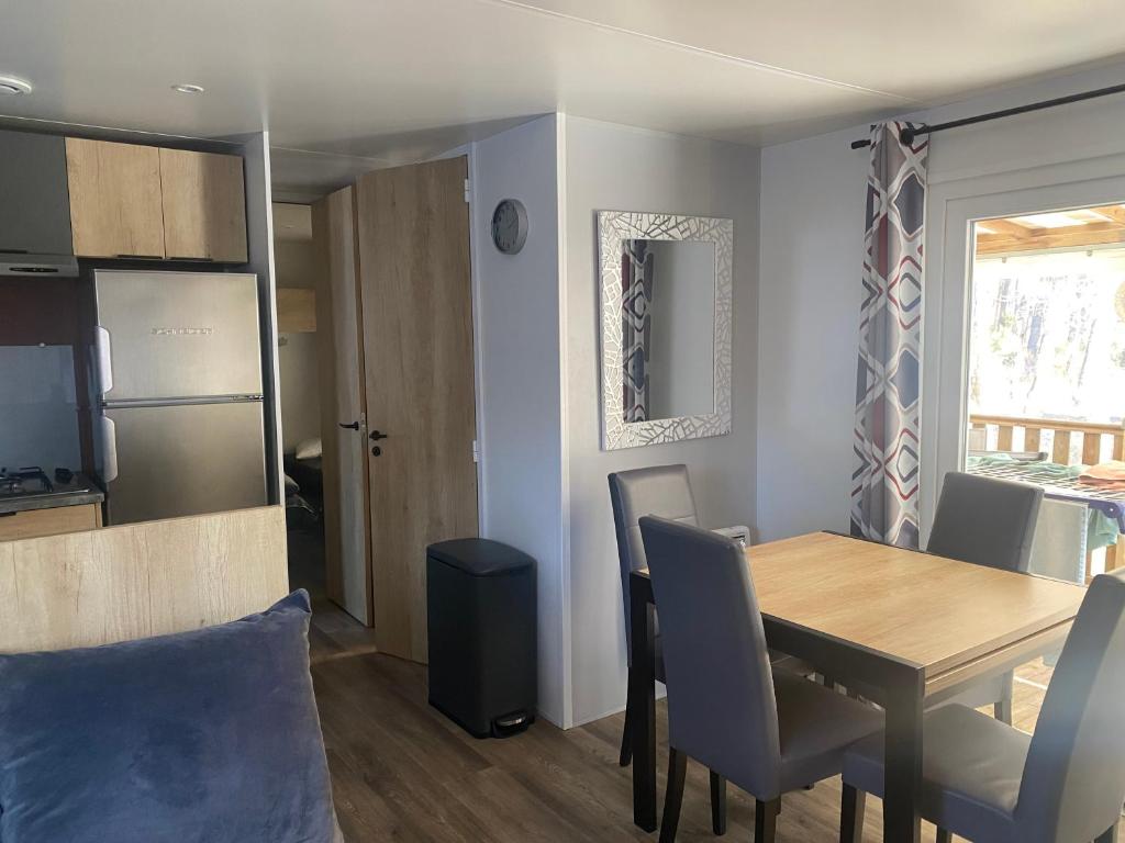 une salle à manger et une cuisine avec une table et des chaises dans l'établissement MH 007 ELITE 3 chambres dont suite parentale et 2 salles de bain sur magnifique parcelle dans camping 4 étoiles, à Saint-Julien-en-Born