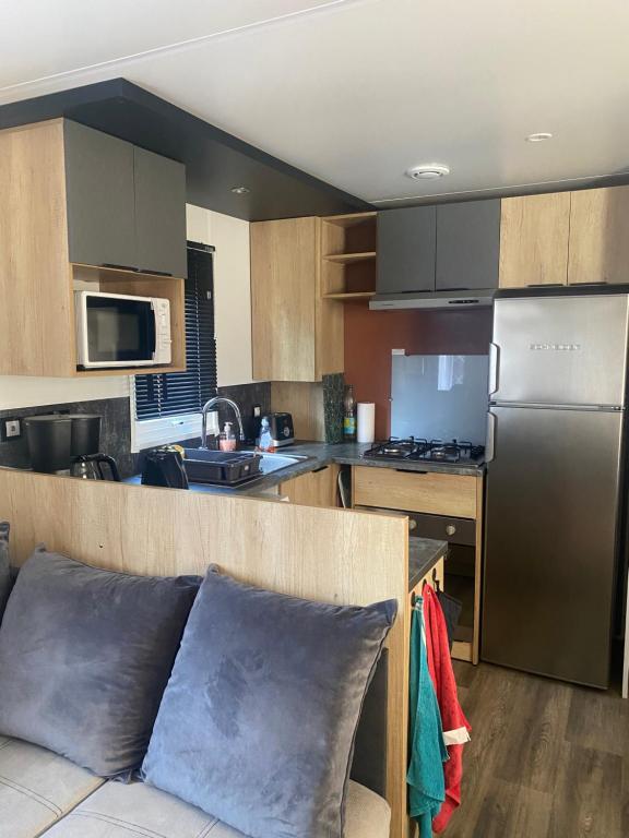 une cuisine avec un canapé et un réfrigérateur en acier inoxydable dans l'établissement MH 007 ELITE 3 chambres dont suite parentale et 2 salles de bain sur magnifique parcelle dans camping 4 étoiles, à Saint-Julien-en-Born 18 autres photos