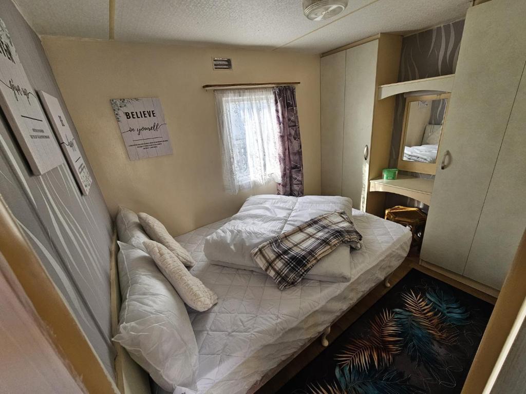 a small bed in a small room with a window at Ingoldmells -Caravan- Sleeps 6 - Seaside - Parking in Skegness