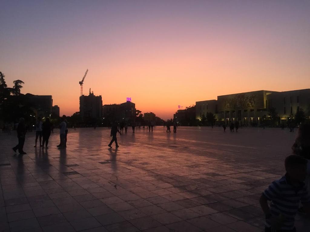 a group of people walking in a square at sunset at Modern apartment in the heart of Tirana in Tirana