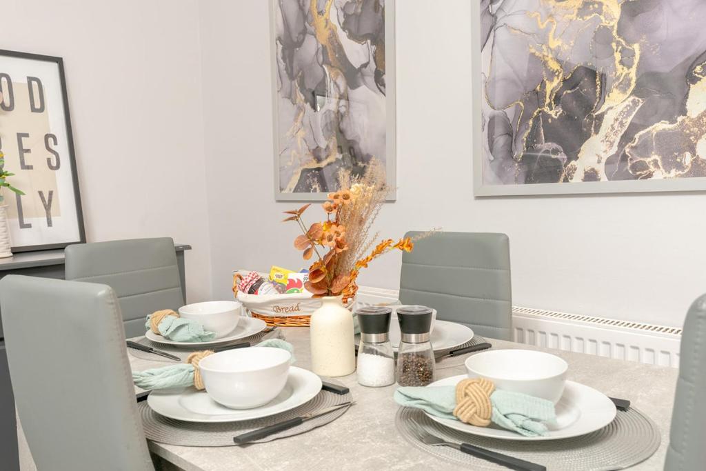 ein Esstisch mit Tellern, Tassen und Stühlen in der Unterkunft Brierfield Cottage in Brierfield