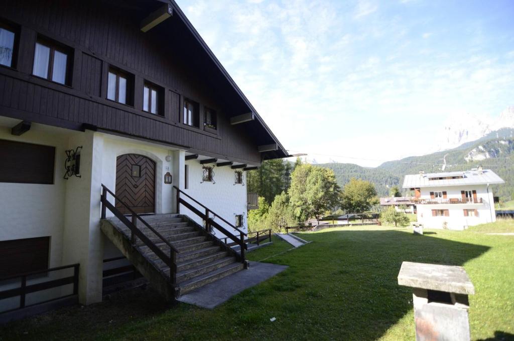 un bâtiment avec un escalier et une cour en gazon dans l'établissement Cà Mughi Studio, à Zuel