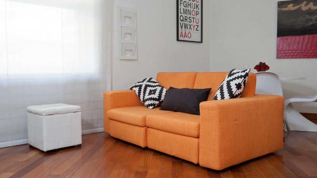 un divano arancione con due cuscini in soggiorno di Italianway-Dogana a Milano