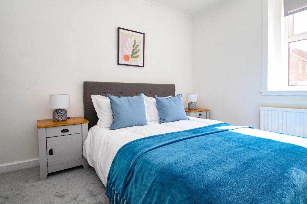 a bedroom with a bed with a blue blanket at 3-Bed Apartment - Near Clyde Shipyard - 25 min Glasgow Airport in Greenock