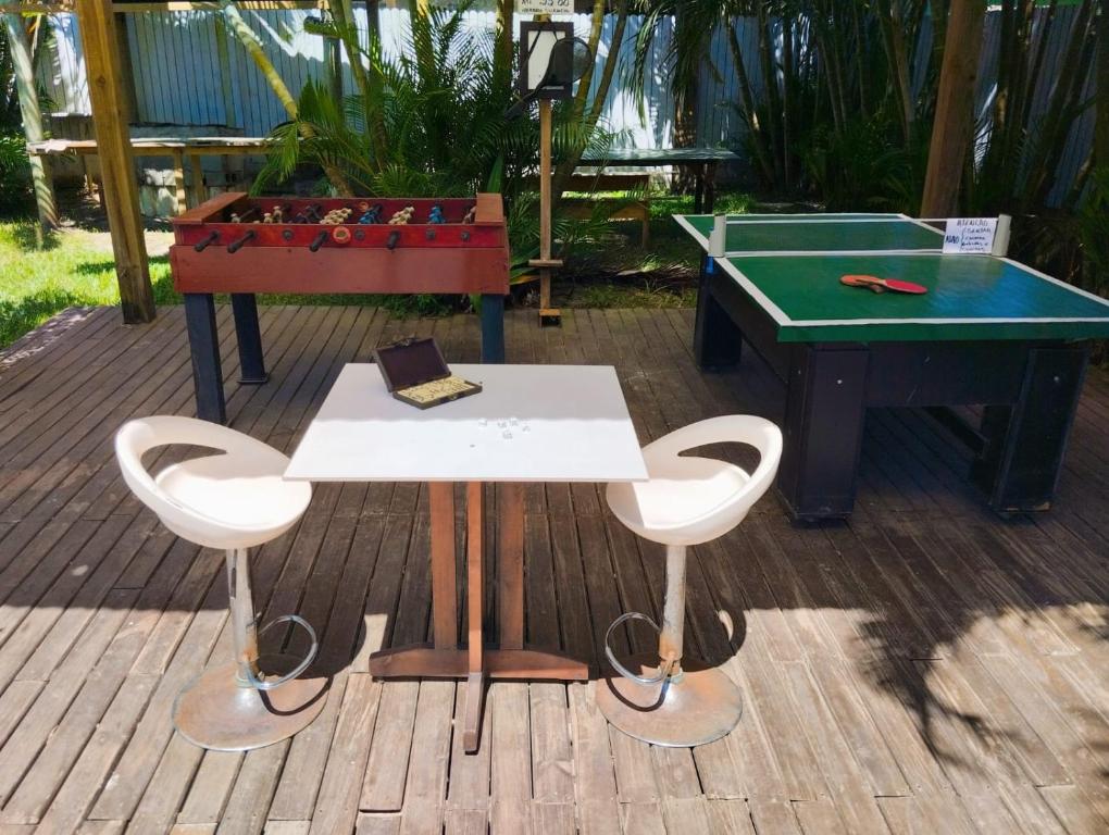 a table and two stools next to a pool table at Pousada Horizontes do Rosa in Praia do Rosa