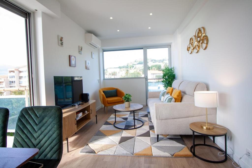 un salon avec un canapé et une télévision dans l'établissement Luxury 1 Bed Apt Seafront Escape in Cannes, à Cannes