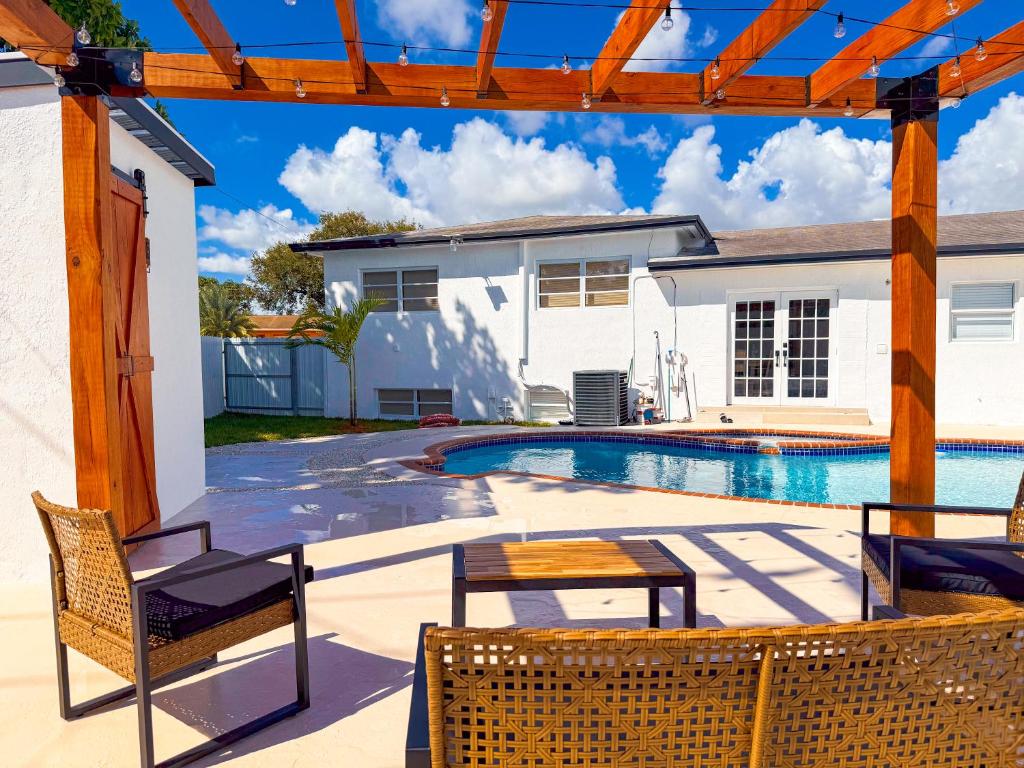 une piscine avec des chaises et une maison dans l'établissement Hard Rock Villa Pool, Game Room & Beach Fun, à Miami Gardens