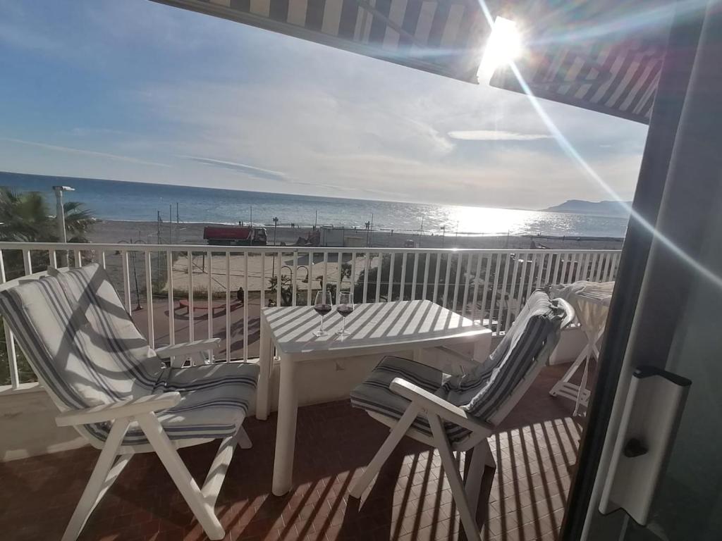 two chairs and a table on a balcony with the beach at A 10 passi dal mare in Ventimiglia