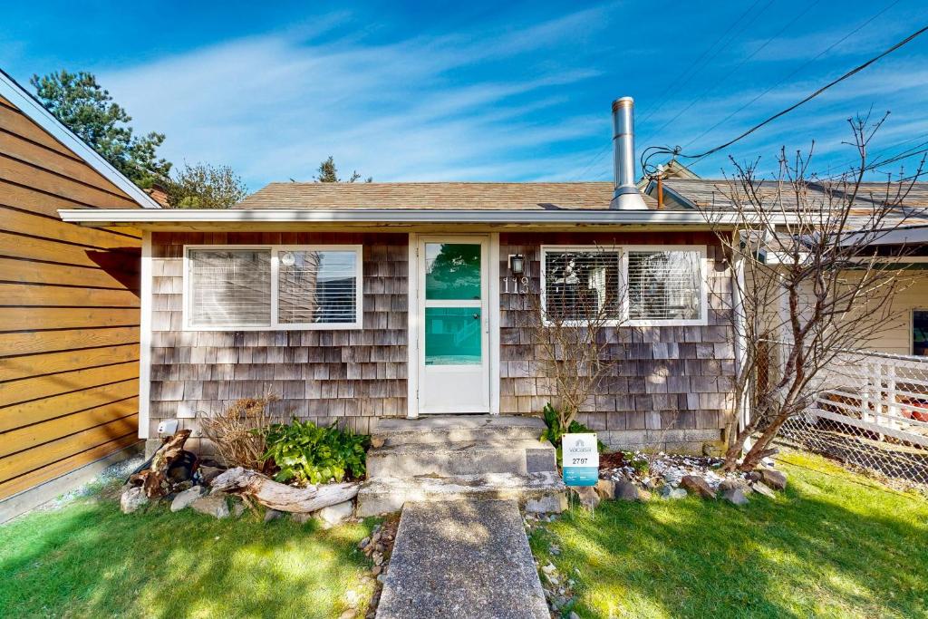a house with a white door and a yard at 4th Avenue Beach Cottage in Rockaway Beach