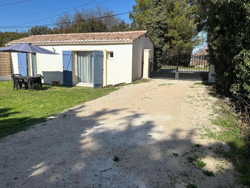 a small white house with a table and an umbrella at Maison de vacances en campagne in Cavaillon