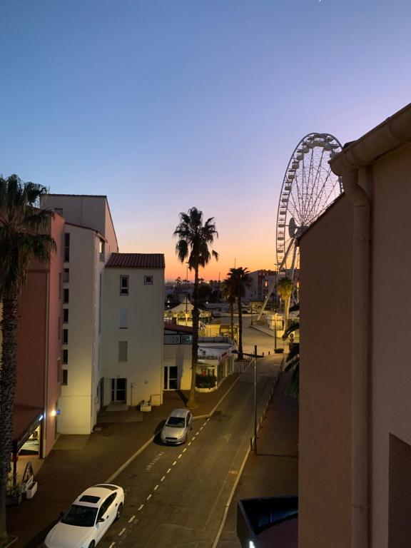 une grande roue et des voitures garées dans une rue de la ville dans l'établissement Richelieu 4, piscine, parking, port & resto a pied, au Cap d'Agde