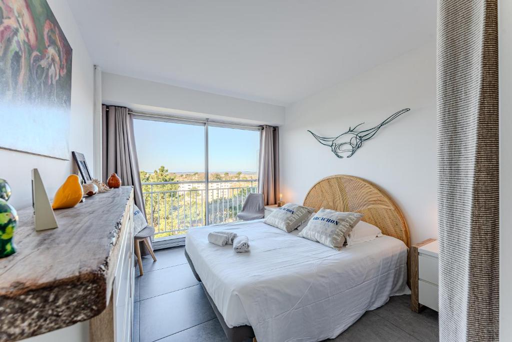 une chambre avec un lit et une grande fenêtre dans l'établissement Appartement vue bassin, à Arcachon