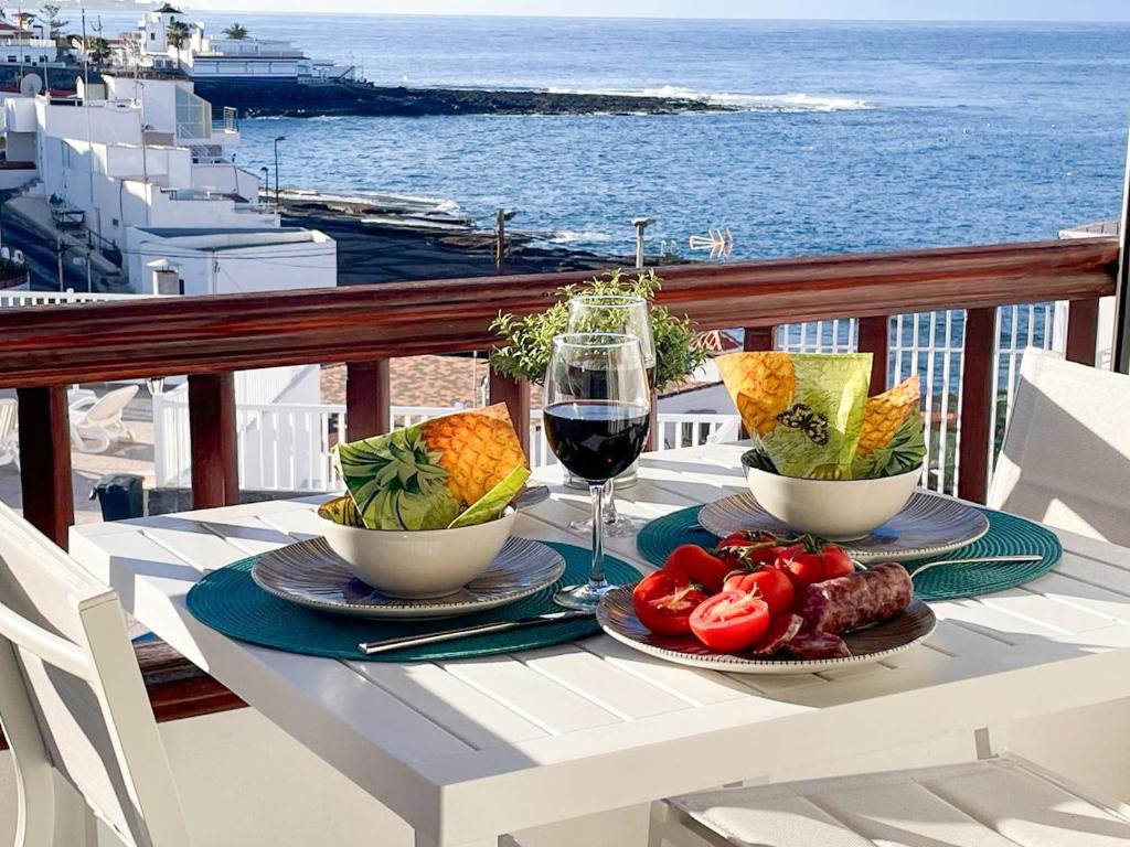 a table with two plates of food and a glass of wine at Ocean View La Caleta in Adeje