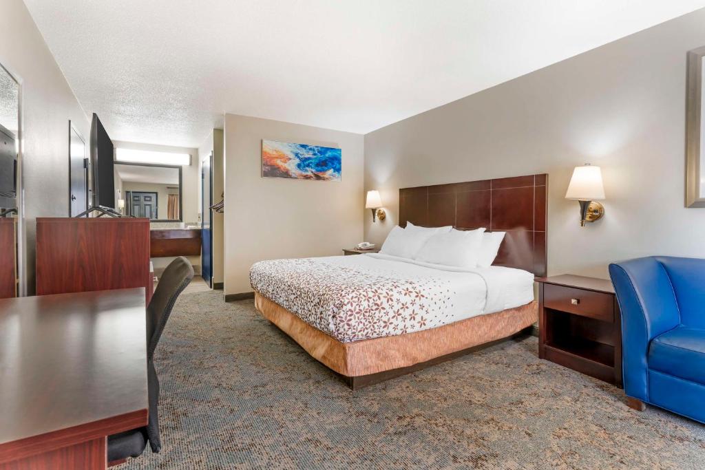 a hotel room with a bed and a blue chair at Best Western Royal Inn in Chattanooga