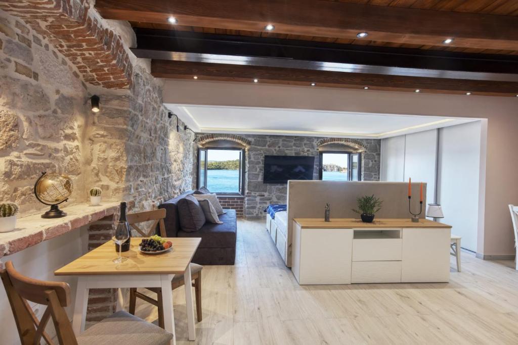 cocina y sala de estar con pared de piedra en Apartman Sun 2, en Šibenik