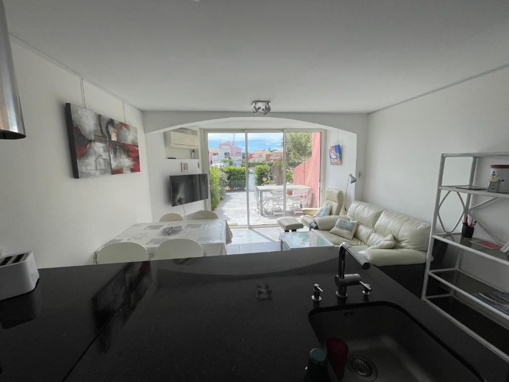 Il dispose d'une cuisine et d'un salon avec un évier et un canapé. dans l'établissement DOUCEUR DU RIVAGE - 6pers - Histoire de Clés, au Cap d'Agde