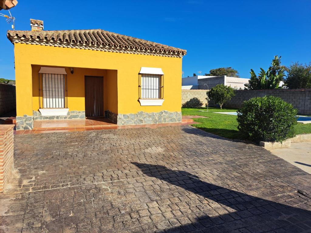a yellow house with a brick driveway at Villa Encanto Chiclana in Novo Sancti Petri