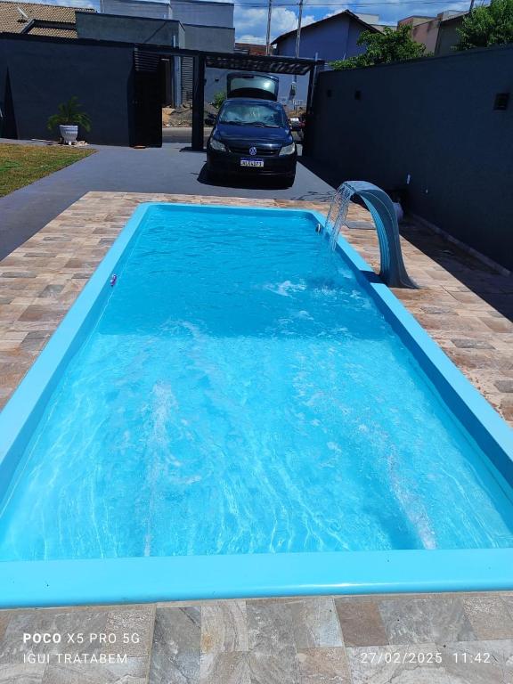 a swimming pool with a car in a driveway at Cantinho Guimarães in Olímpia