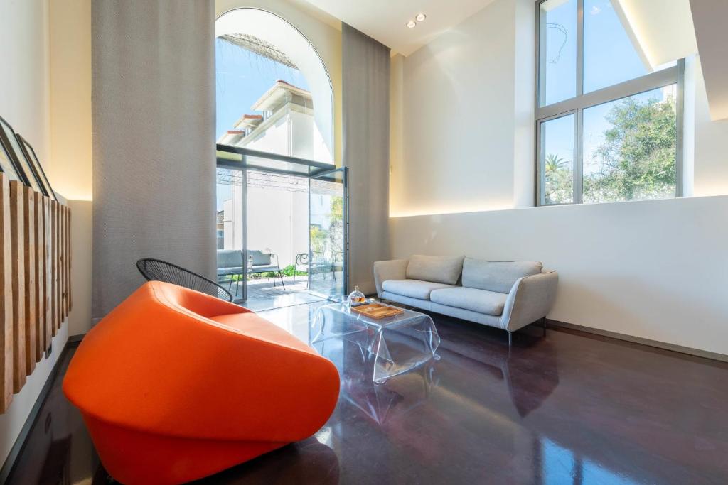 un salon avec une chaise orange et une table en verre dans l'établissement 1-Br 75m Duplex with Pool, à Cannes
