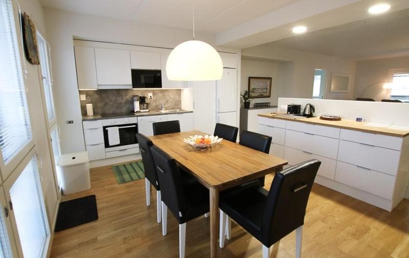 une cuisine et une salle à manger avec une table et des chaises en bois dans l'établissement Uniikki kolmio Aurajokinäkymin, à Turku