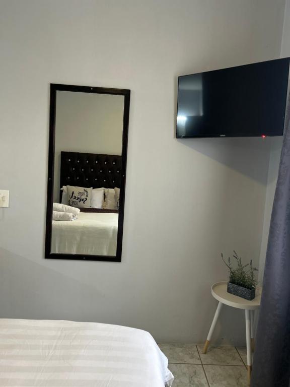 a mirror on the wall of a bedroom with a bed at Skyfly Bed & Breakfast in Manzini