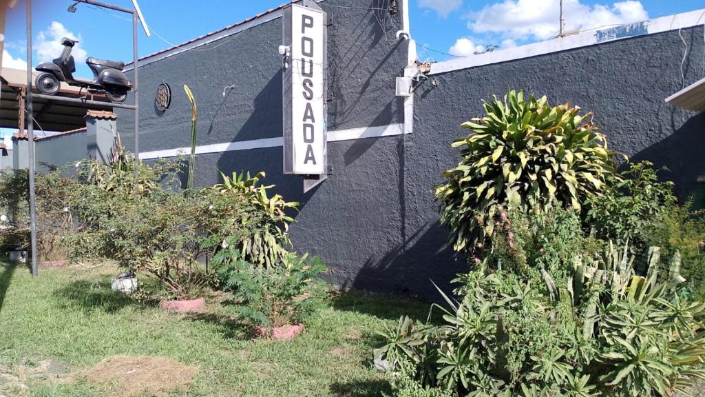 um sinal na lateral de um edifício com plantas em Pousada Rout Bikers Penedo em Penedo