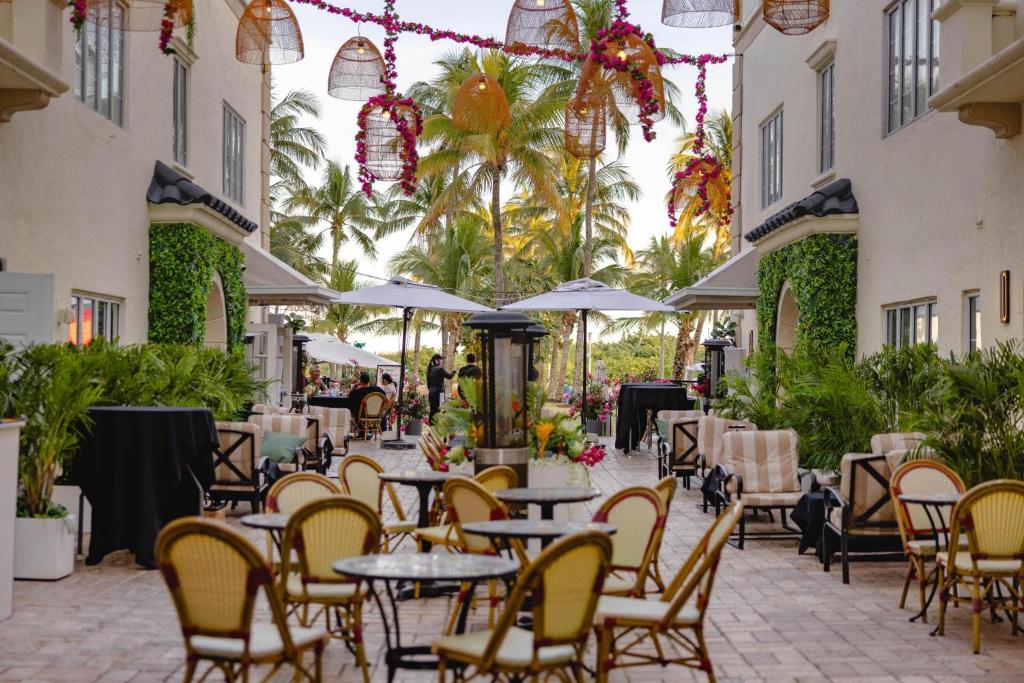 a patio with tables and chairs and palm trees at Hotel Ocean in Miami Beach