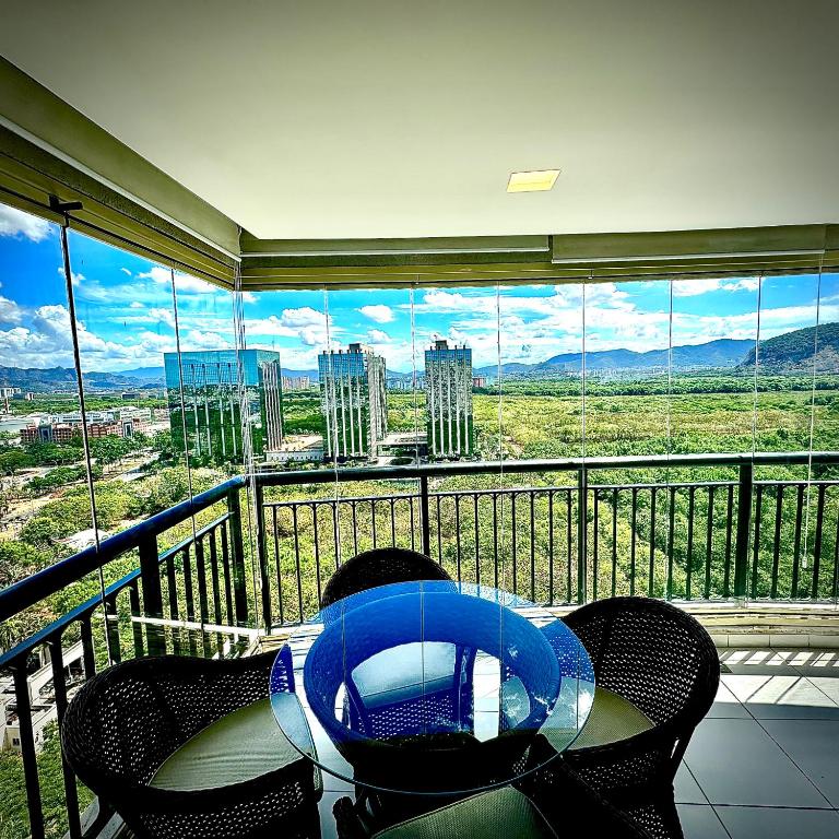 a balcony with a table and chairs and a large window at Península View Lazer Commodity in Barra da Tijuca