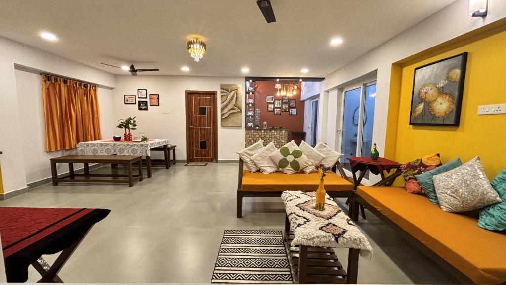 a living room with yellow walls and couches and a table at Ta Cabana Beach house-Pondicherry in Pondicherry