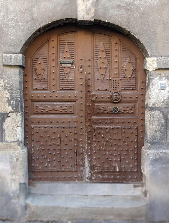 - une grande porte en bois dans un bâtiment en pierre dans l'établissement Superbe appartement duplex en hyper centre, au Puy-en-Velay