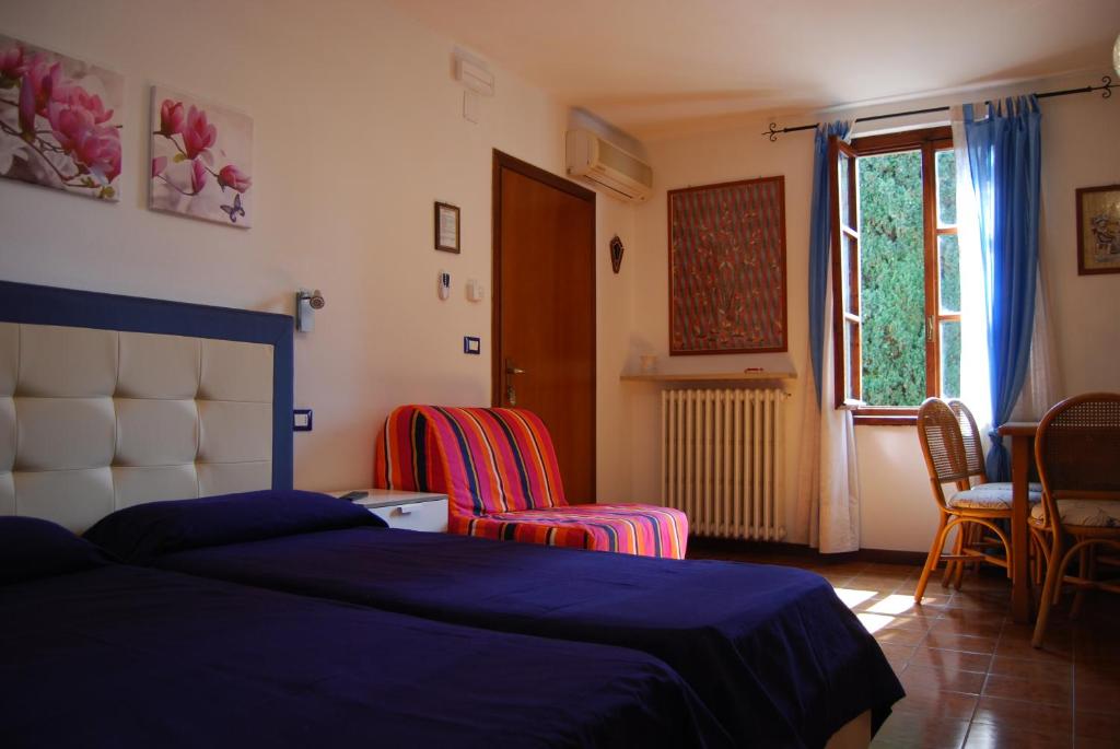 a bedroom with a bed and chairs and a window at Appartamenti Corneliani in Sirmione