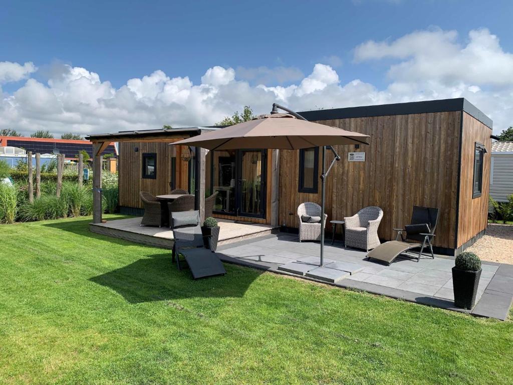 a house with an umbrella and chairs on a lawn at Chalet in Domburg near Dunes in Koudekerke