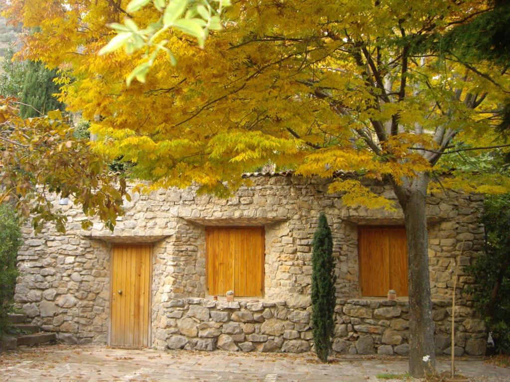 a stone building with two doors and a tree at La Casita con piscina privada de tres dormitorios in Torres