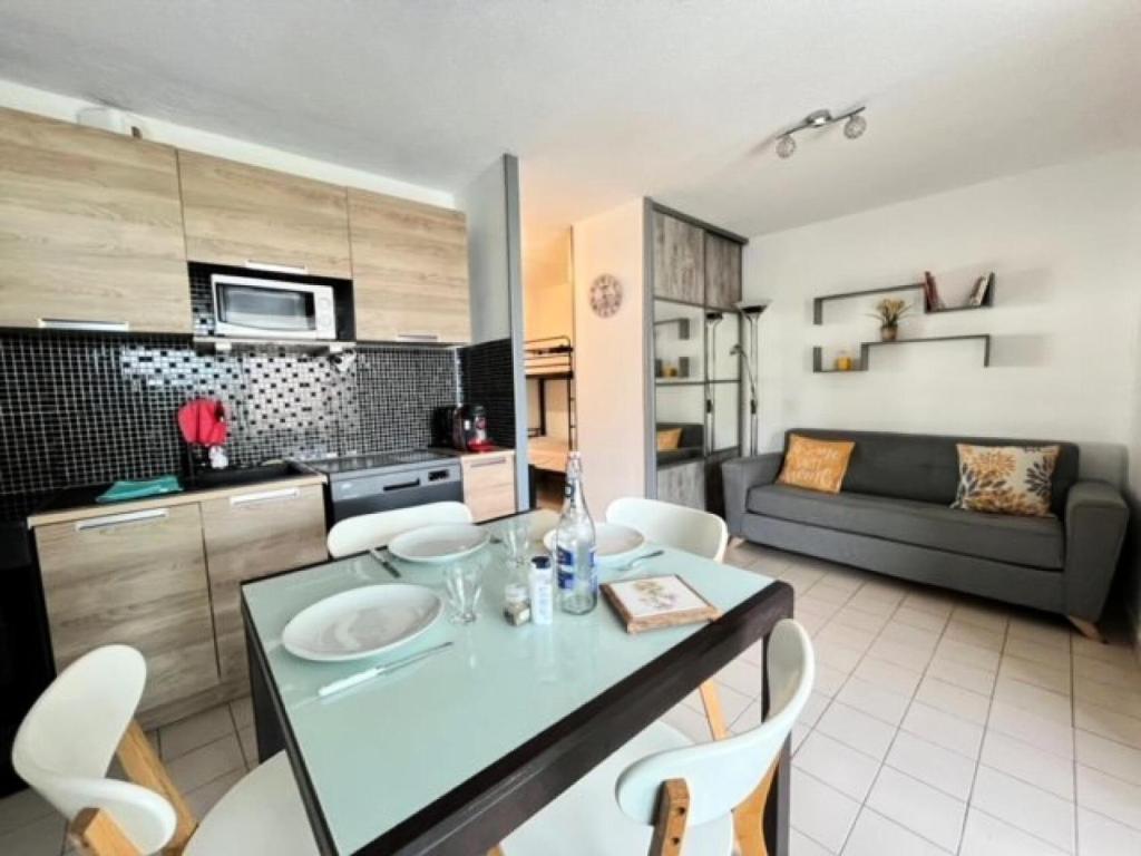 une cuisine et un salon avec une table et des chaises dans l'établissement Résidence Le Beaulieu - Appartement 6 couchages à Port Camargue MAE-5351, au Grau-du-Roi
