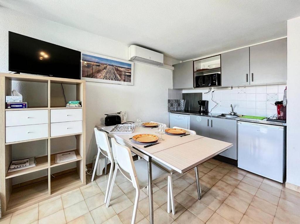 une cuisine avec une table et des chaises dans une pièce dans l'établissement Résidence Le Lagon Bleu - T2 dans résidence avec piscine MAE-6971, au Grau-du-Roi