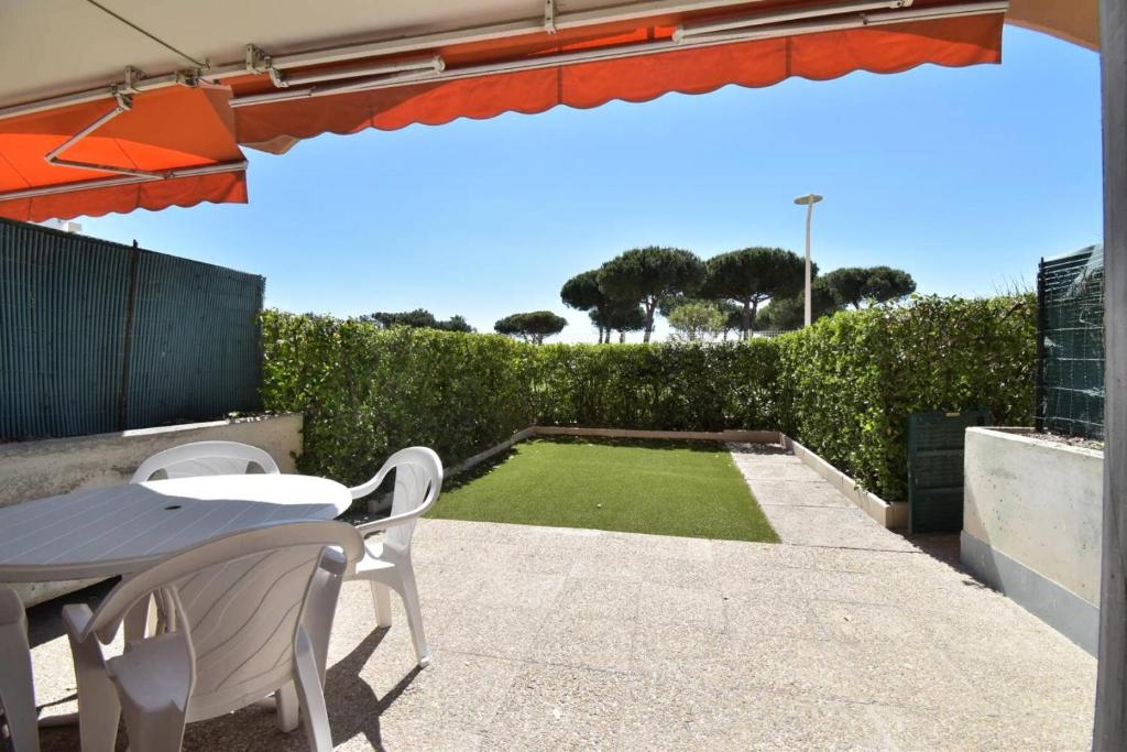 un patio avec un parasol, une table et des chaises dans l'établissement Résidence Le Vincent - Rez de jardin proche plage et centre ville du Grau du roi MAE-7051, au Grau-du-Roi
