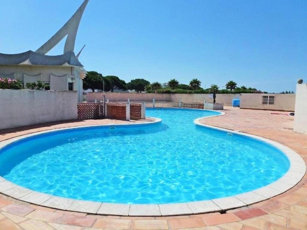 une piscine avec un moulin à vent en arrière-plan dans l'établissement Résidence Le Chabian - Port Camargue T2 rénové, tout équipé, en 1ère ligne mer, plage sud à 50m, piscine, tennis, climatisé MAE-7061, au Grau-du-Roi