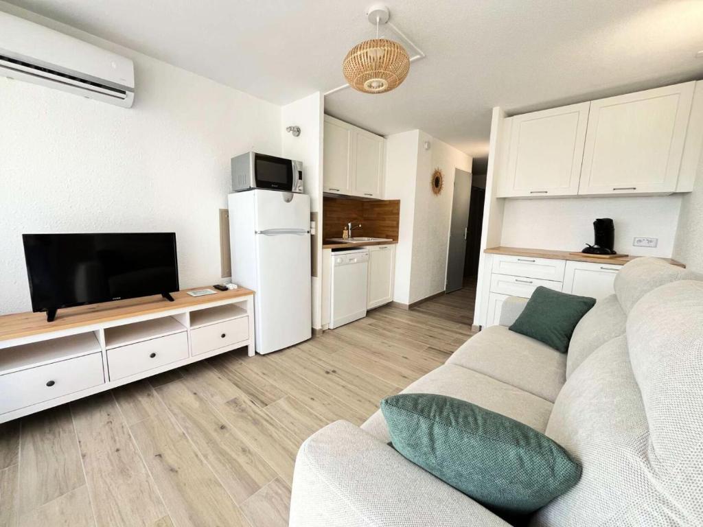 un salon blanc avec un canapé et une télévision dans l'établissement Résidence Le Lagon Bleu - Studio cabine 4 couchages avec piscine MAE-7111, au Grau-du-Roi