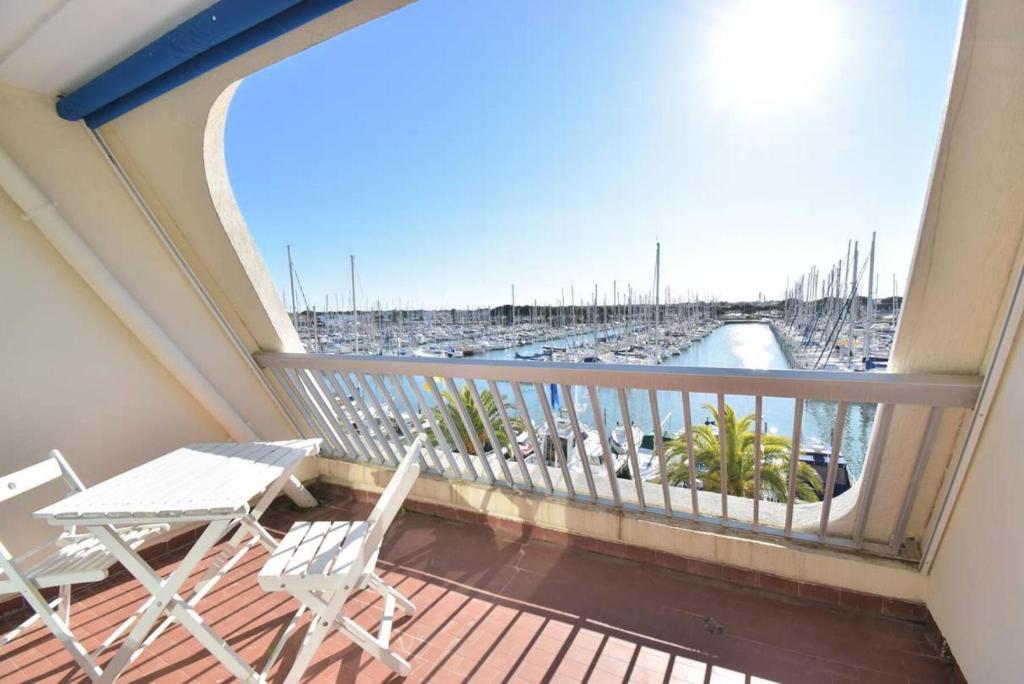 d'un balcon avec deux chaises blanches et une vue sur le port de plaisance. dans l'établissement Résidence Le Grand Pavois - Studio cabine vue port à Port Camargue MAE-7171, au Grau-du-Roi