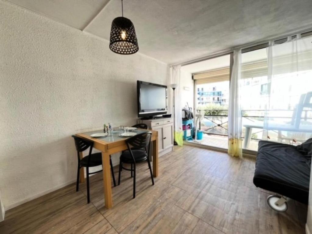 un salon avec une table et une télévision dans l'établissement Résidence Le Lagon Bleu - Studio cabine avec piscine au Lagon Bleu MAE-7231, au Grau-du-Roi