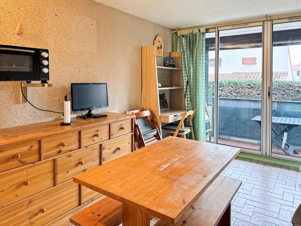 Cette chambre dispose d'une commode en bois, d'une télévision et d'une table. dans l'établissement Résidence Le Lagon Bleu - Studio dans résidence avec piscine MAE-7241, au Grau-du-Roi