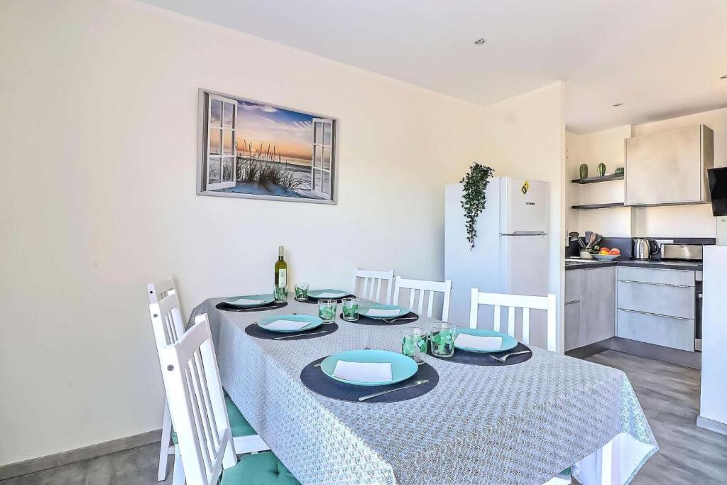 une table à manger avec un chiffon bleu et blanc dans l'établissement Résidence Les Suzannes - Appartement T3 moderne au Grau du roi MAE-9871, au Grau-du-Roi