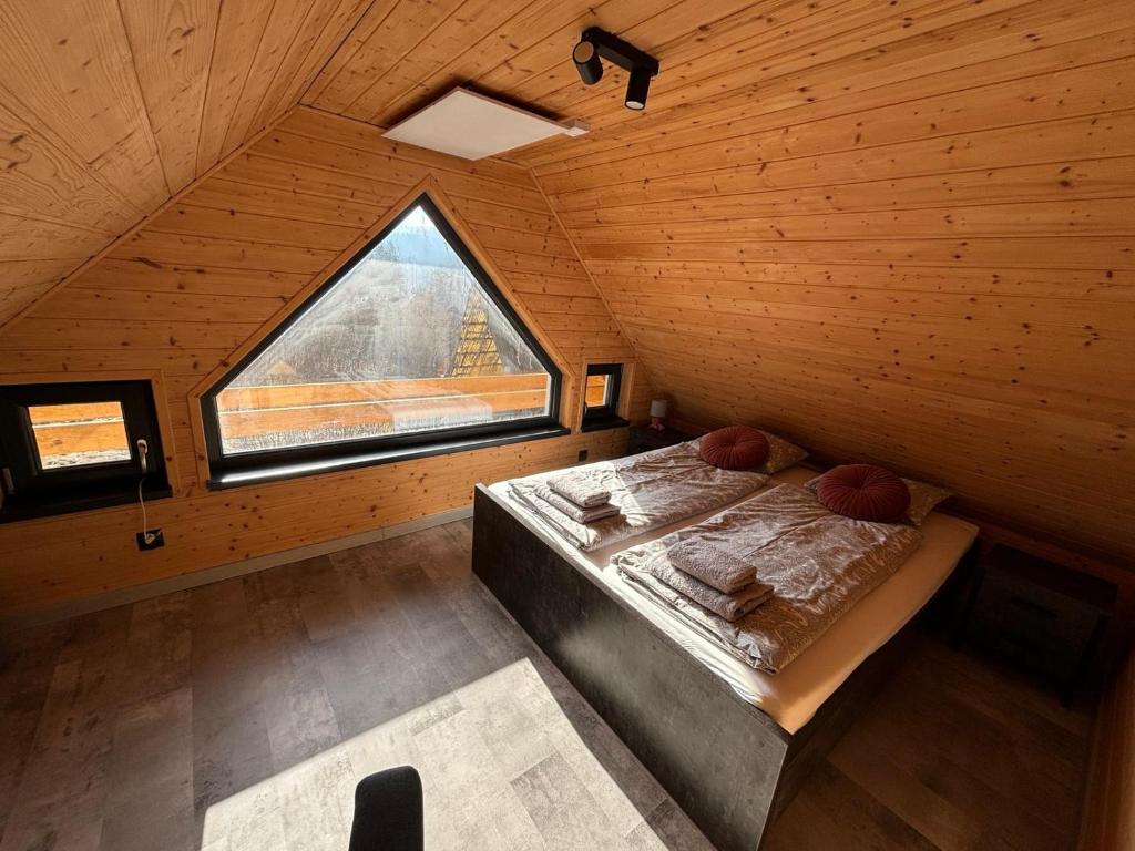 a bedroom with a bed in a wooden room with a window at Górskie chatki w Wiśle in Wisła